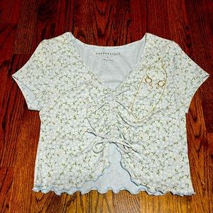 Light blue with white daisy flowers. Cropper shirt with tie in front.